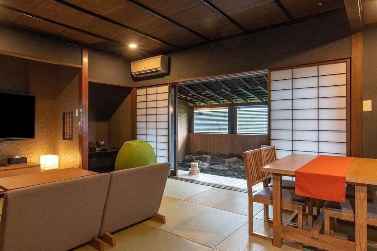 Et traditionelt japansk rum med tatamigulv, en tatami-madras sofa, et lavt træbord og en skydedør med udsigt til et vandfald.