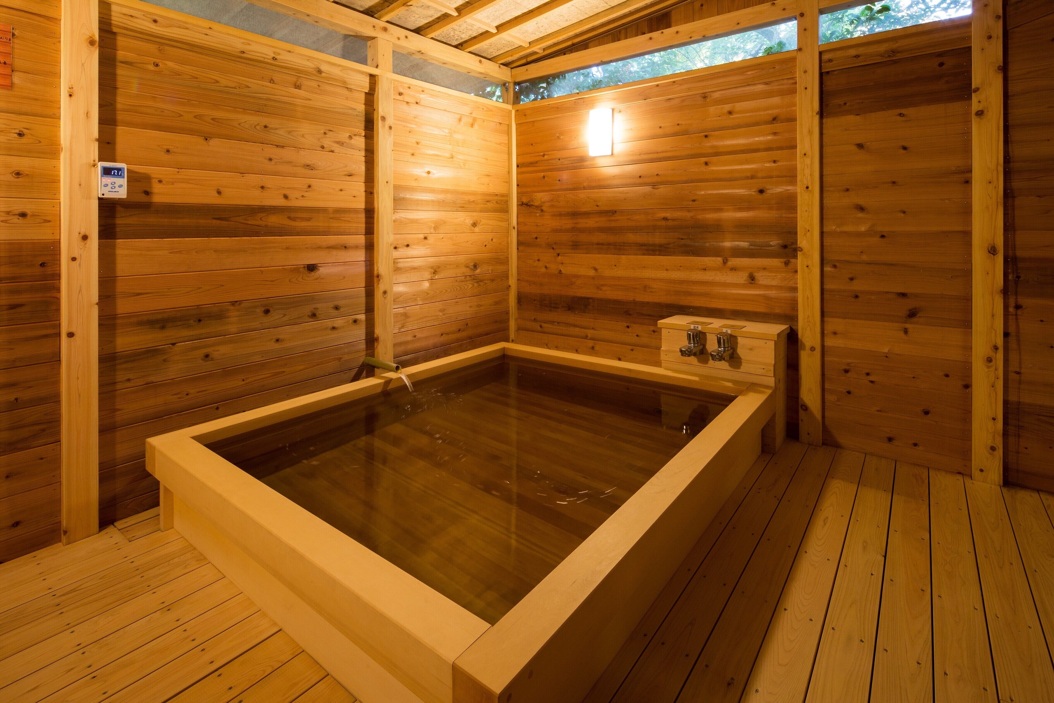 A wooden sauna with a rectangular hot tub, wooden walls, and a tiled floor.