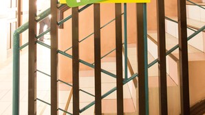 A sign for GV Hotels with a green and yellow design, mounted on a metal structure with a staircase in the background. - GV Hotel Masbate (Masbate City)