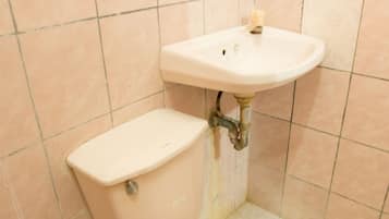 A bathroom with a toilet and sink, tiled walls, and a sign indicating water conservation.
