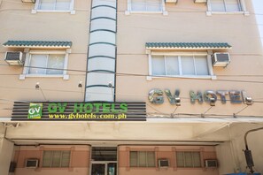 A hotel building with a sign reading "GV Hotels" and a website address.