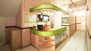 A reception area with a green counter, a clock, a computer, and a bulletin board. - GV Hotel Masbate (Masbate City)