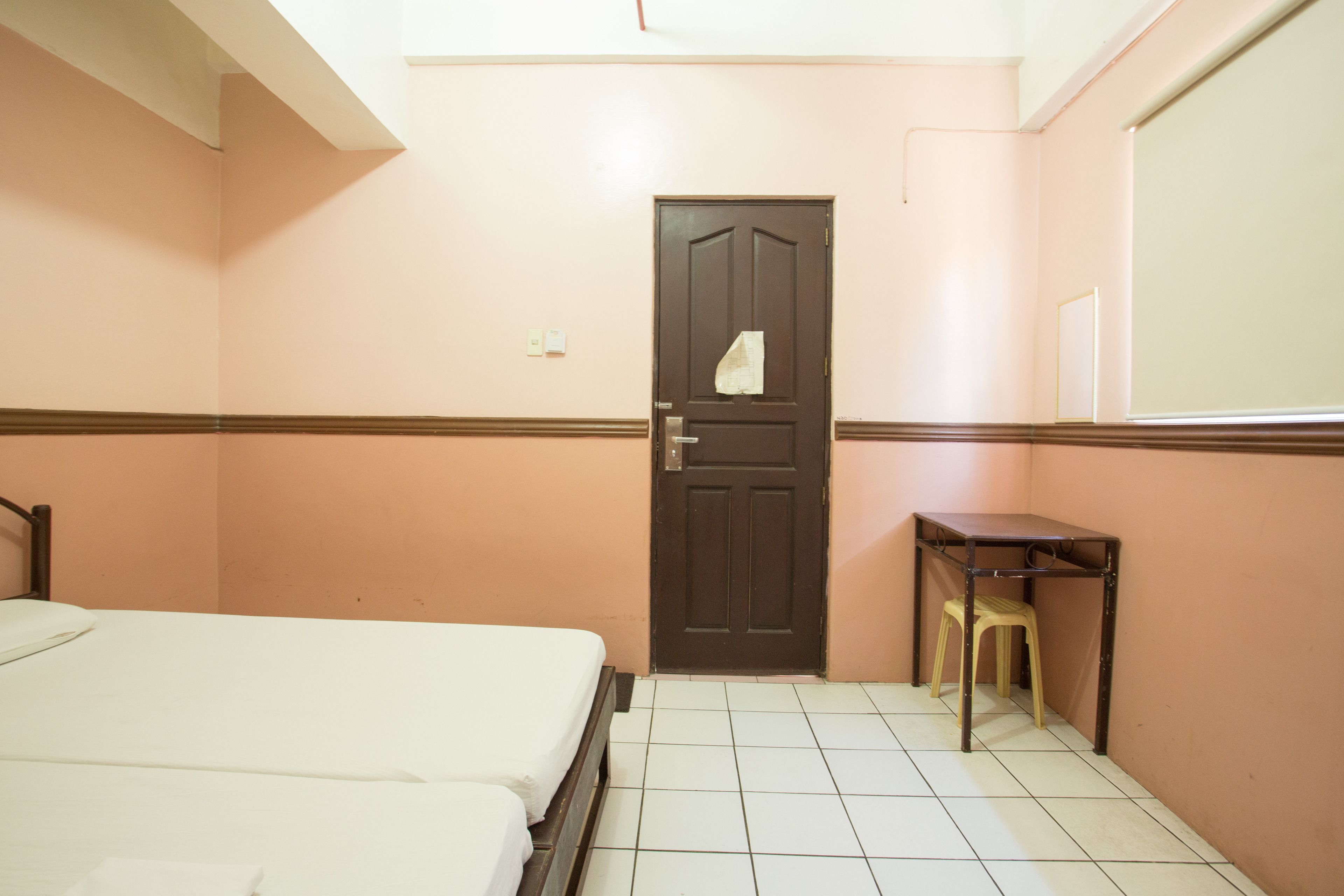 Una habitación pequeña y limpia con una cama, un escritorio y una puerta.