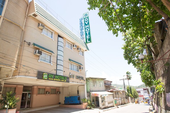 A hotel with a sign reading "GV HOTEL" and a website address.