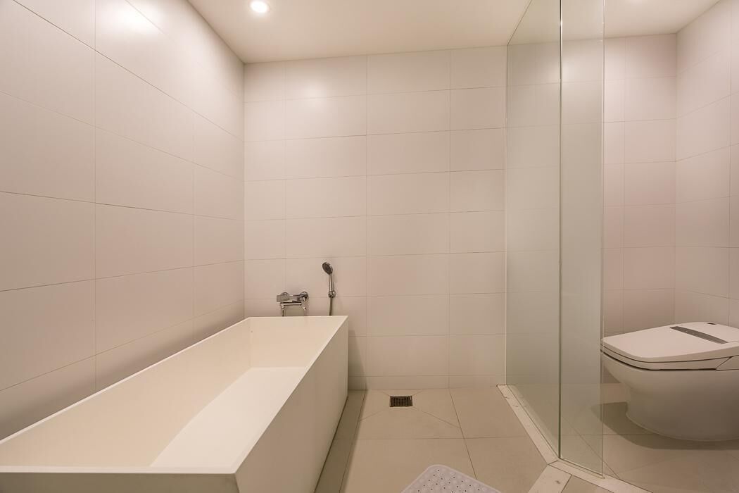 Een moderne badkamer met een ruime badkuip, een toilet en een douchecabine van glas.