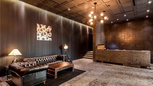 A modern lobby with a leather sofa, a coffee table, a reception desk, and a patterned carpet. - Hotel the May (Namyangju)