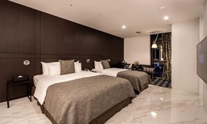 Een moderne hotelkamer met twee bedden, donker houten lambrisering, een marmeren vloer, een klein bureau en uitzicht op de stad 's nachts.