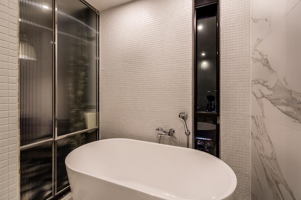 A modern bathroom with a freestanding bathtub, tiled walls, and a glass shower enclosure.