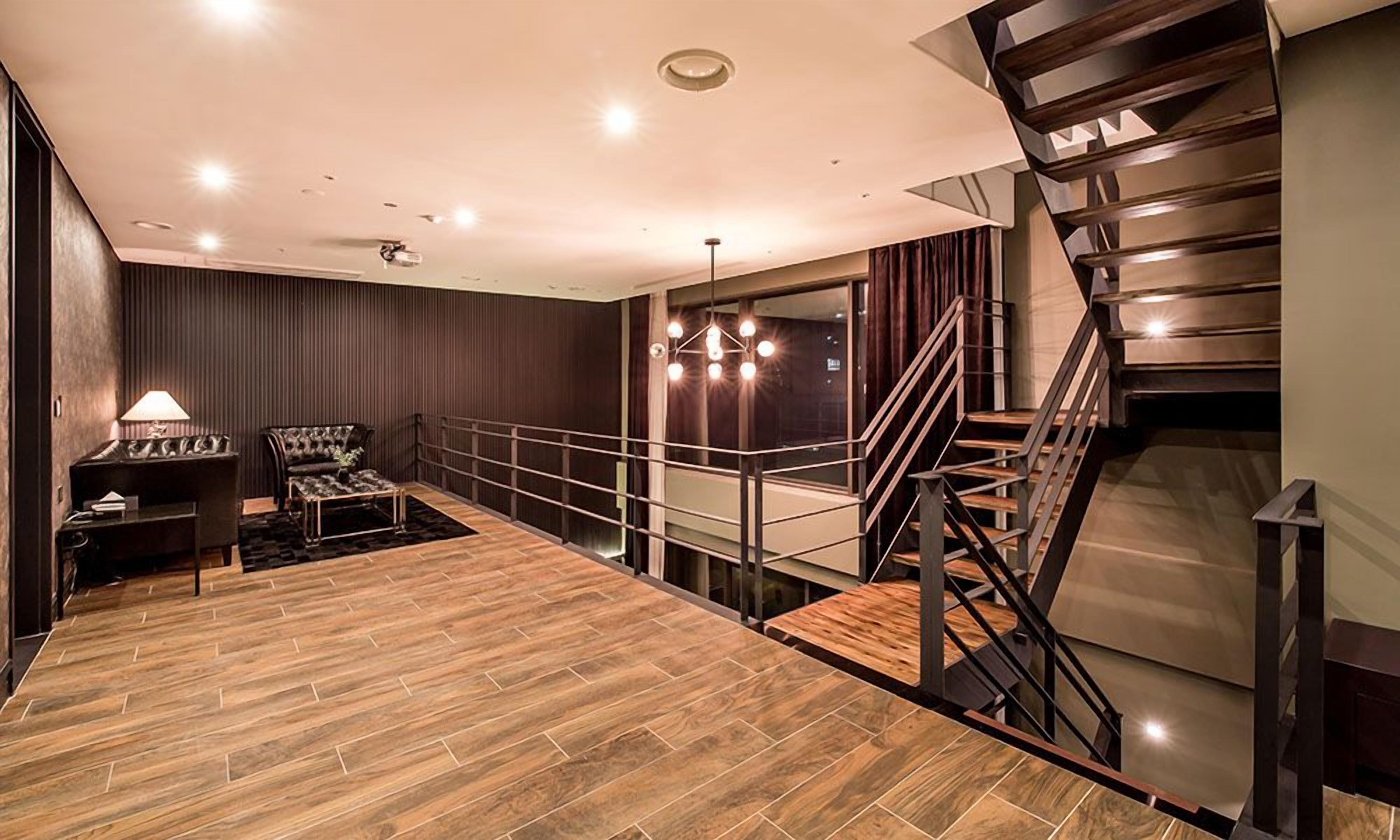 Ein modernes Interieur mit Holzboden, einer Treppe und einer Sitzecke mit einer Lampe.