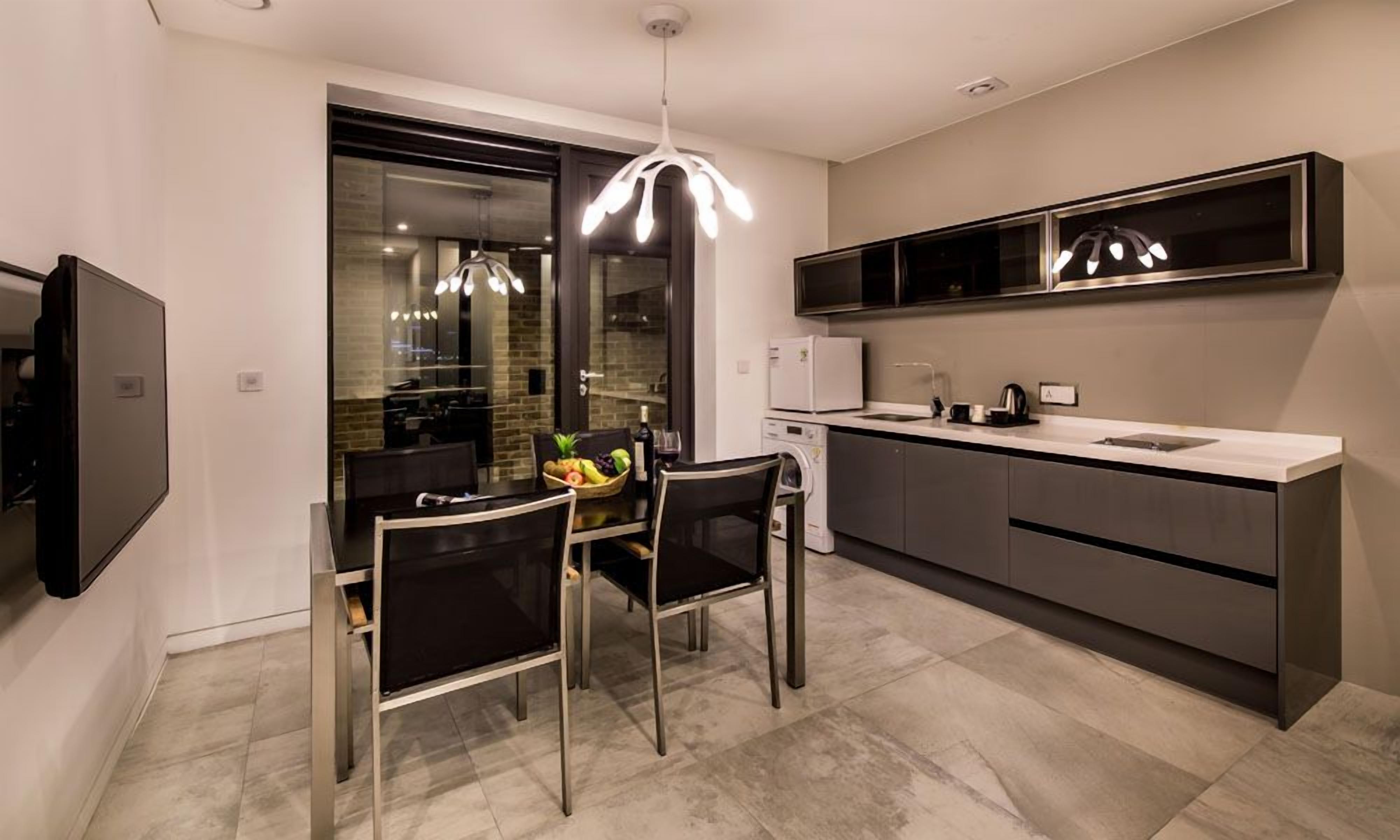 A modern kitchen with a dining area, stainless steel appliances, and a pendant light.