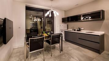 A modern kitchen with a dining area, stainless steel appliances, and a pendant light.