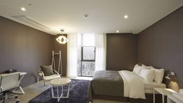 Un hotel moderno con una cama grande, un escritorio, una silla y vistas a la ciudad desde la ventana.