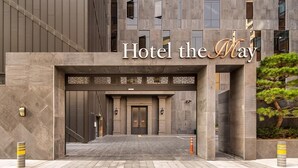 A modern hotel entrance with a stone facade, a central door, and a sign reading "Hotel the May". - Hotel the May (Namyangju)