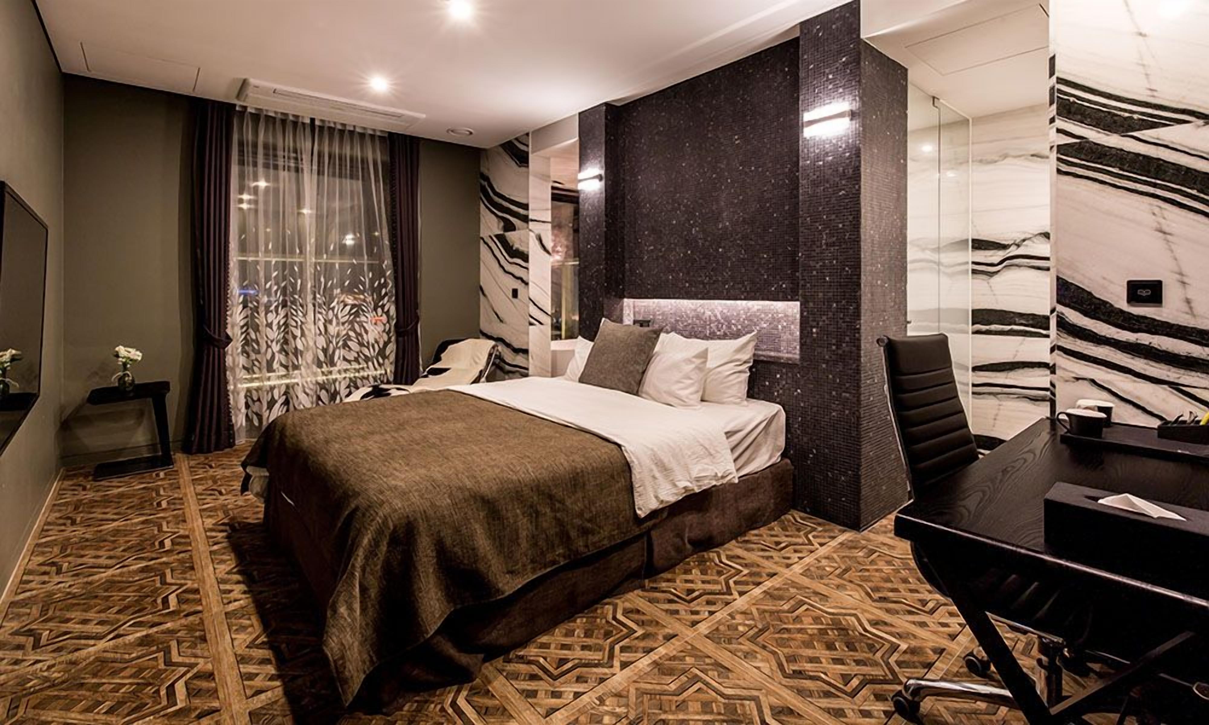 A modern hotel room with a large bed, a desk, and a chair.