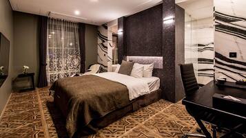 A modern hotel room with a large bed, a desk, and a chair.