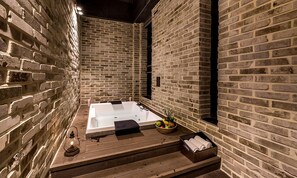 A spa area with a hot tub, wooden flooring, and a brick wall. - Hotel the May (Namyangju)