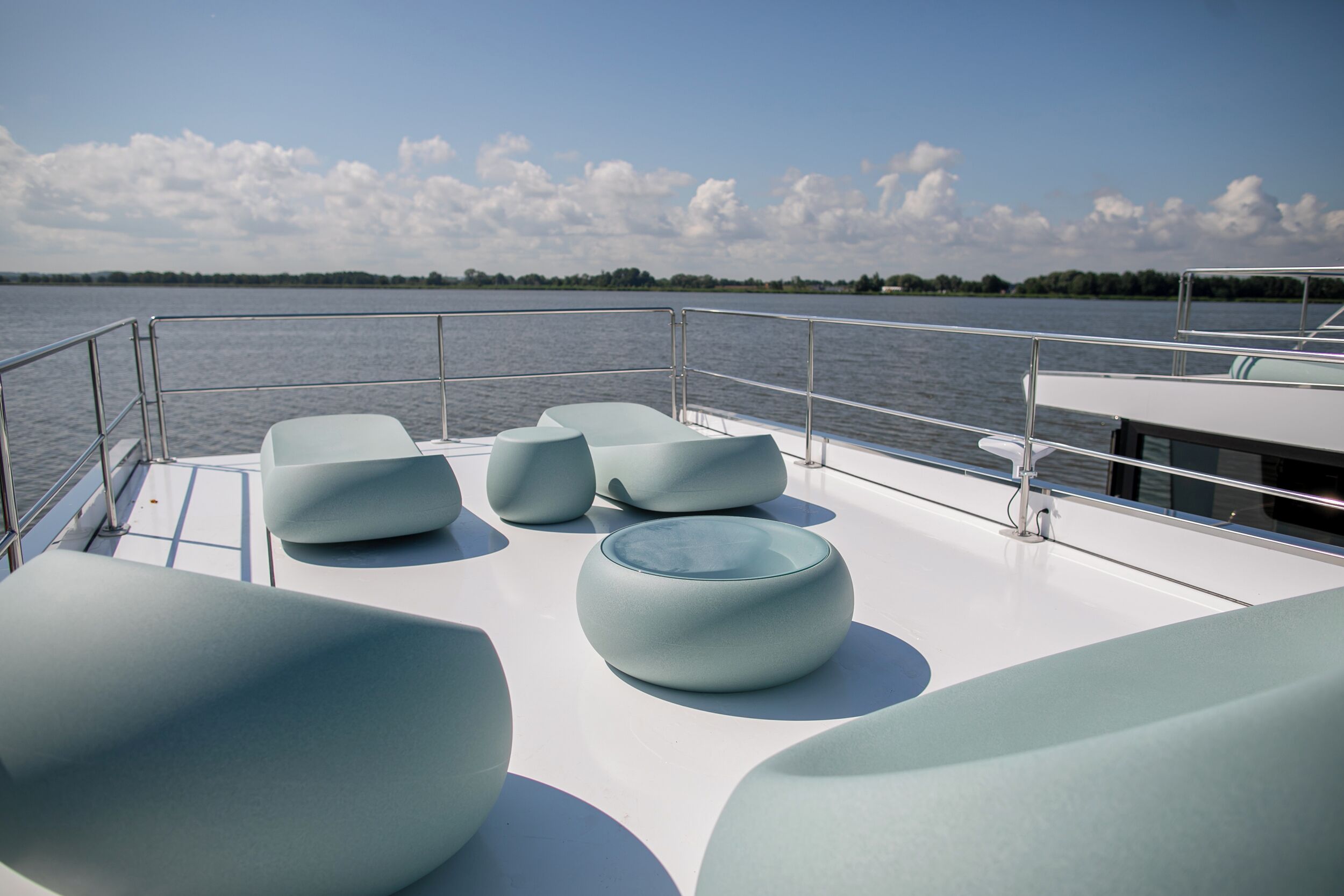A boat deck with modern, light-colored seating areas and a metal railing.