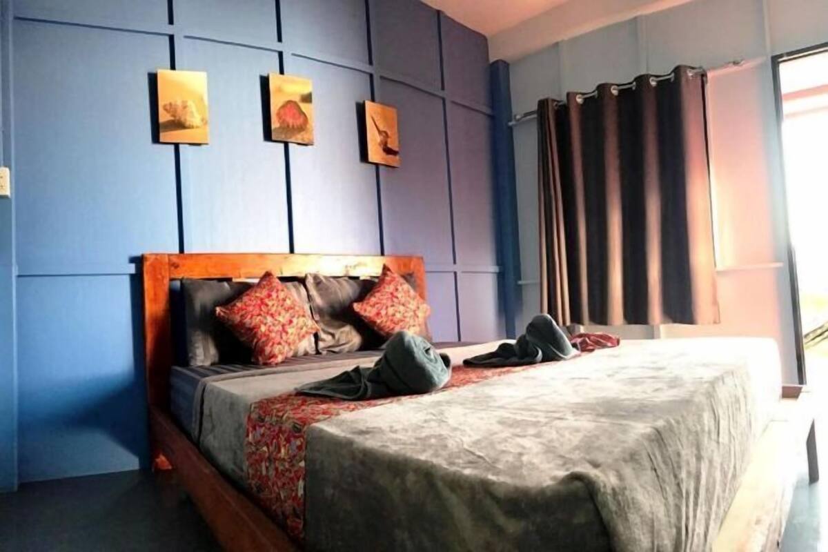 A bedroom with a bed, a headboard, and a window with curtains.