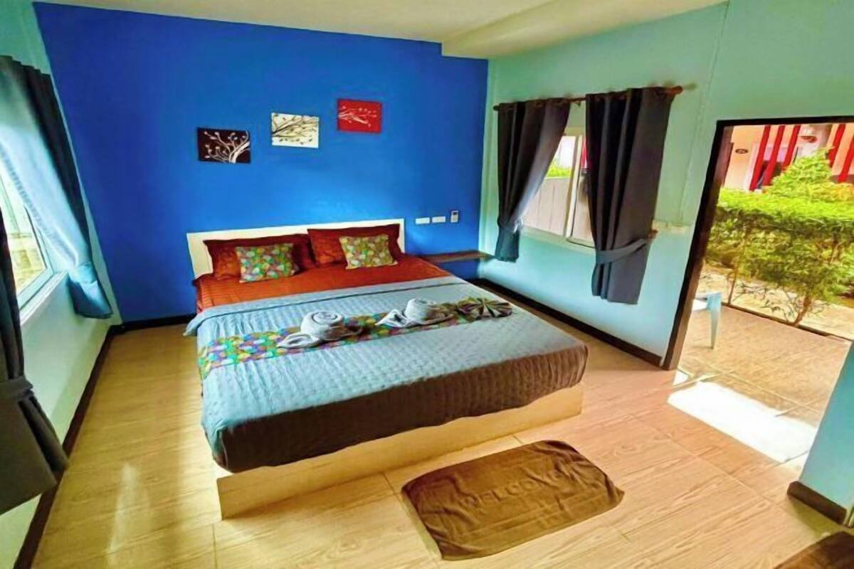 A bedroom with a bed, a window, and a view of greenery outside.