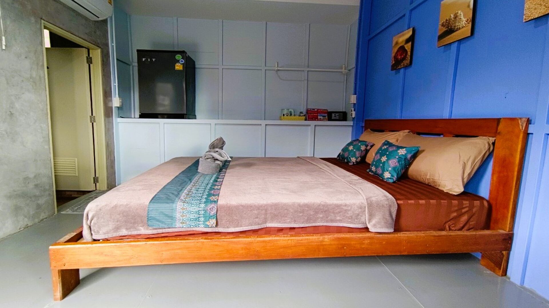 A bedroom with a wooden bed, a fitted wardrobe, and a small kitchenette area.