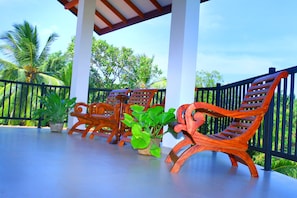 A covered outdoor seating area with wooden chairs and potted plants. - Nature Resort Tissamaharama (Thissamaharama)
