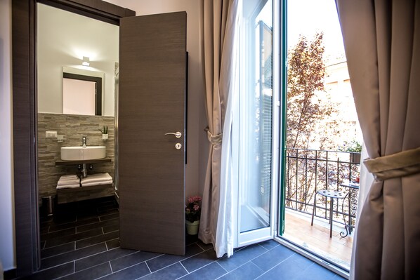 A modern bathroom with a sink, mirror, and a sliding glass door leading to a balcony.