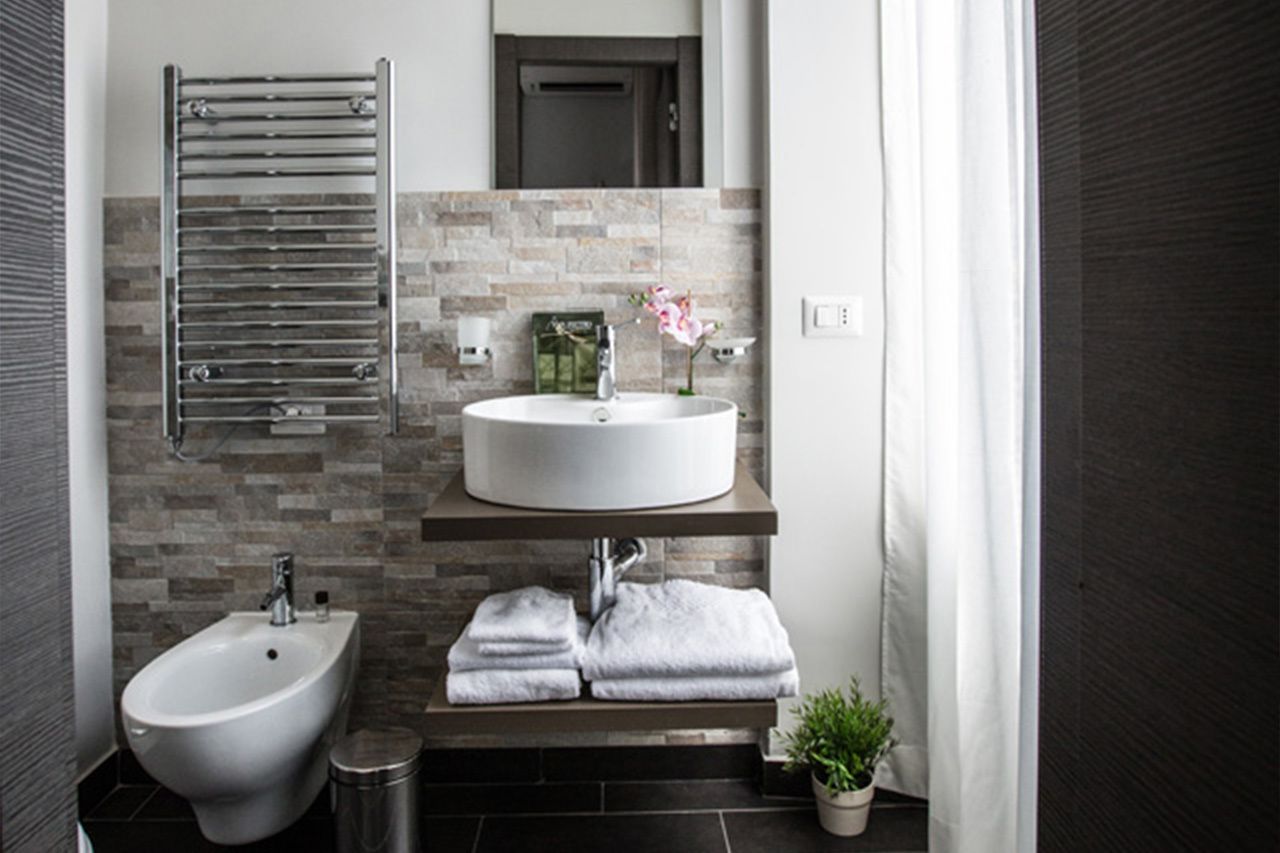 Ein modernes Badezimmer mit einer Tiefspültoilette, einem runden Waschbecken, einem Handtuchhalter und einem Blumentopf.