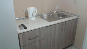 A small kitchenette with a sink, a kettle, and a remote control on the countertop. - Rose Rooms Apart (Istanbul)