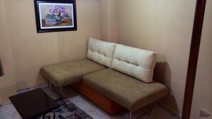 A room with a beige sofa, a small table, and a framed picture on the wall. - Rose Rooms Apart (Istanbul)