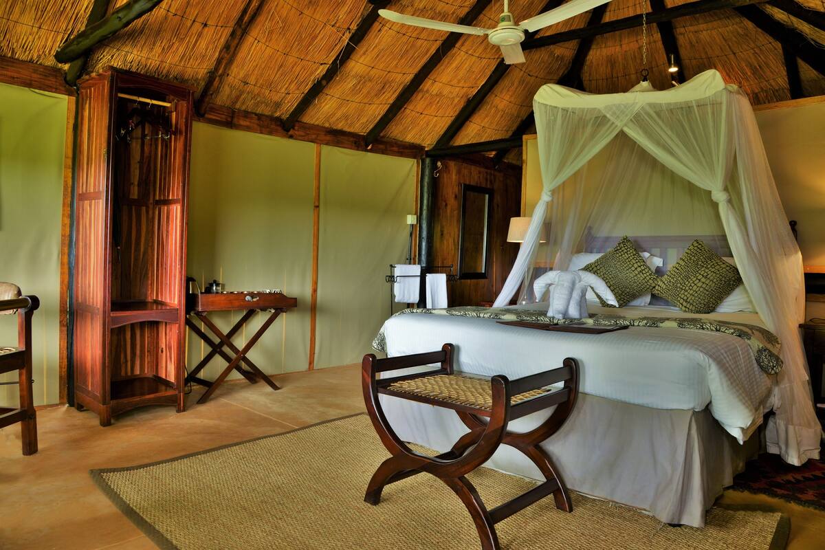 A room with a bed, a wooden chair, a nightstand, a desk, and a wardrobe.