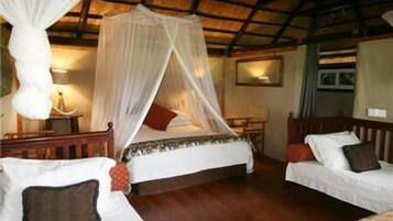 A room with a bed under a canopy, a bedside table with a lamp, and a chair.