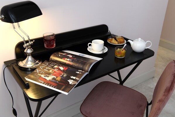 A small, black desk with a magazine, a cup, a teapot, and a plate of croissants. - Grand Hotel Henri - Teritoria (L'Isle-sur-la-Sorgue)