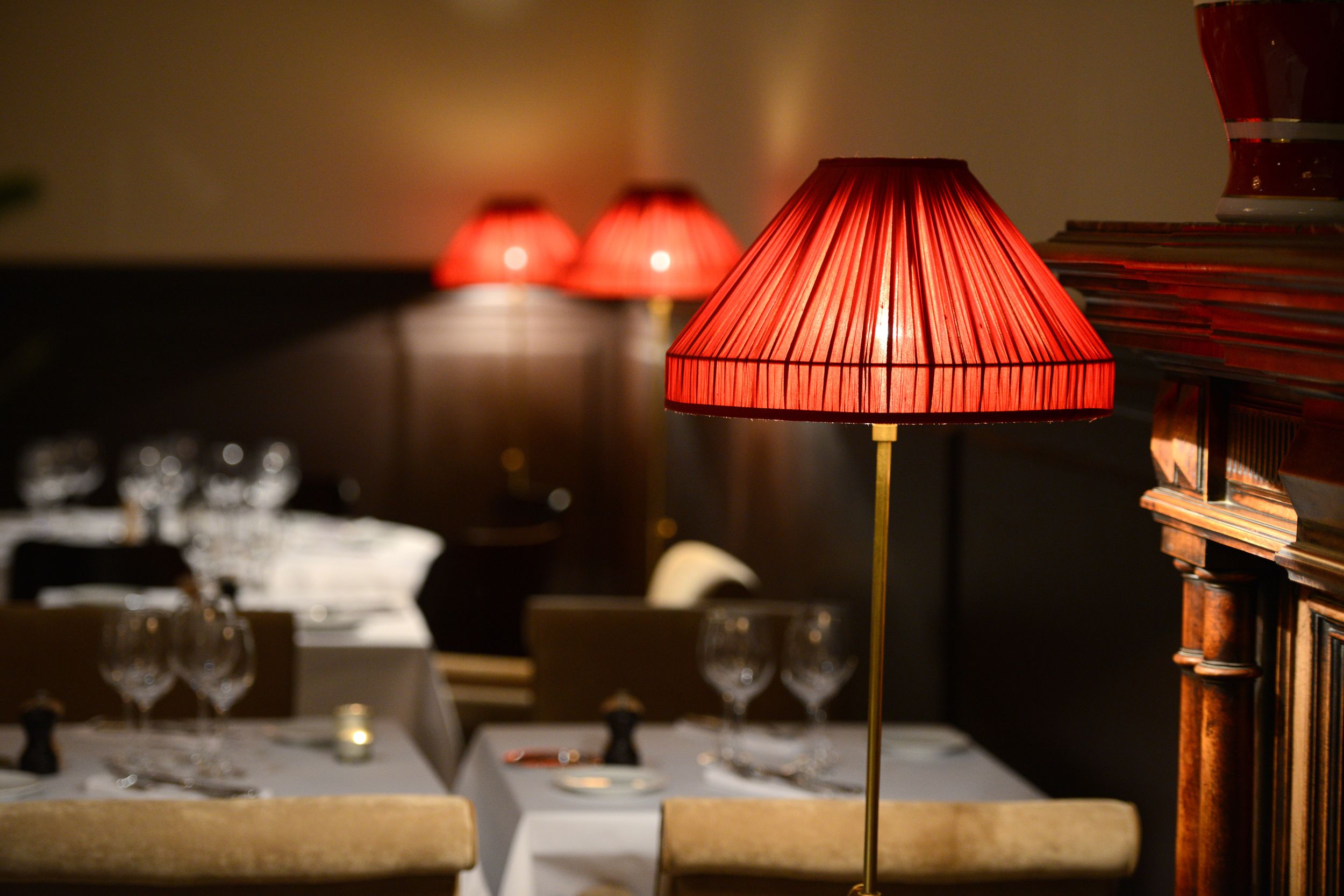 Une table à manger avec une lampe rouge, une bougie et des verres à vin.