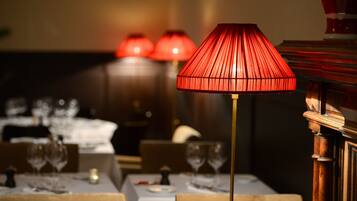 Une table à manger avec une lampe rouge, une bougie et des verres à vin.