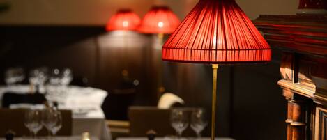 Une table à manger avec une lampe rouge, une bougie et des verres à vin.