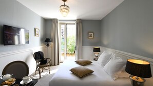 Une chambre d’hôtel comprenant un lit, une télévision, une table à manger avec des articles pour le petit-déjeuner, une chaise et une fenêtre avec des rideaux.