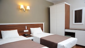 A hotel room with two beds, a wardrobe, a desk, and a wall-mounted lamp. - Deniz Palace Hotel (Istanbul)