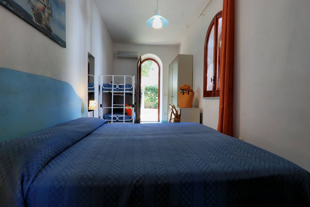 Un dormitorio con una cama litera, un escritorio, una silla y una ventana con cortinas.