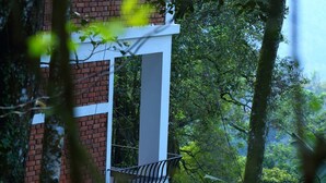 A red brick building with a white balcony. - Madhumanthra Resort (Devikolam)