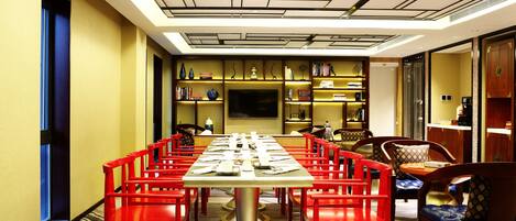 A conference room with a long table, red chairs, and a modern ceiling design.