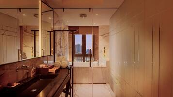 Un baño moderno con un espejo grande, una encimera oscura y vistas a la ciudad a través de una puerta de cristal.