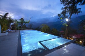Une piscine avec vue sur les montagnes au crépuscule.