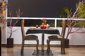 A dining table set for two with chairs, a candle, and a vase with flowers. - Dream Catcher Plantation Resort (Udumbanchola)
