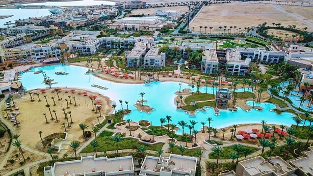 Eine Vogelperspektive eines Resorts mit mehreren Swimmingpools, Palmen und Hotelgebäuden.