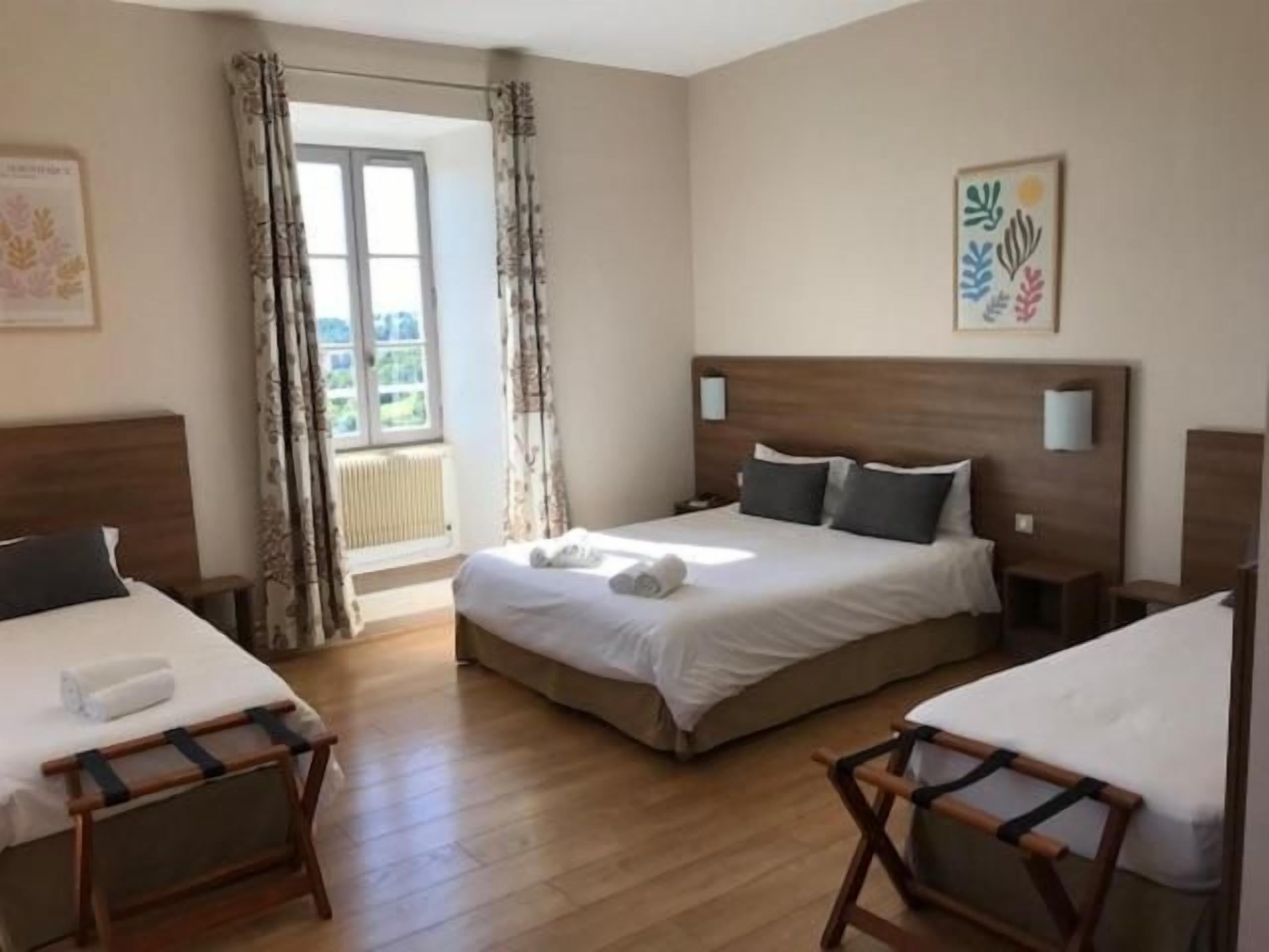 A hotel room with a large bed, two bedside tables, a window with curtains, and a view of the outdoors.