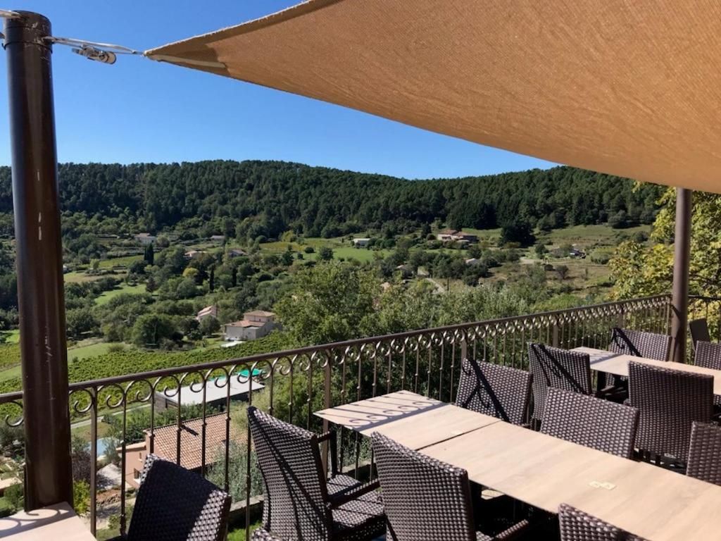 Una terraza con mobiliario exterior, vista a un paisaje montañoso y cielo despejado.