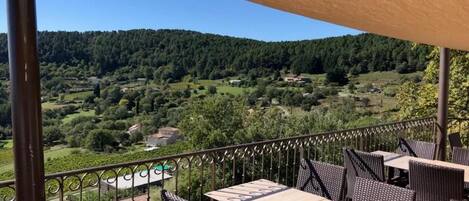 Una terraza con mobiliario exterior, vista a un paisaje montañoso y cielo despejado.