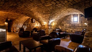 Una habitación acogedora con paredes de piedra, asientos de cuero y chimenea.