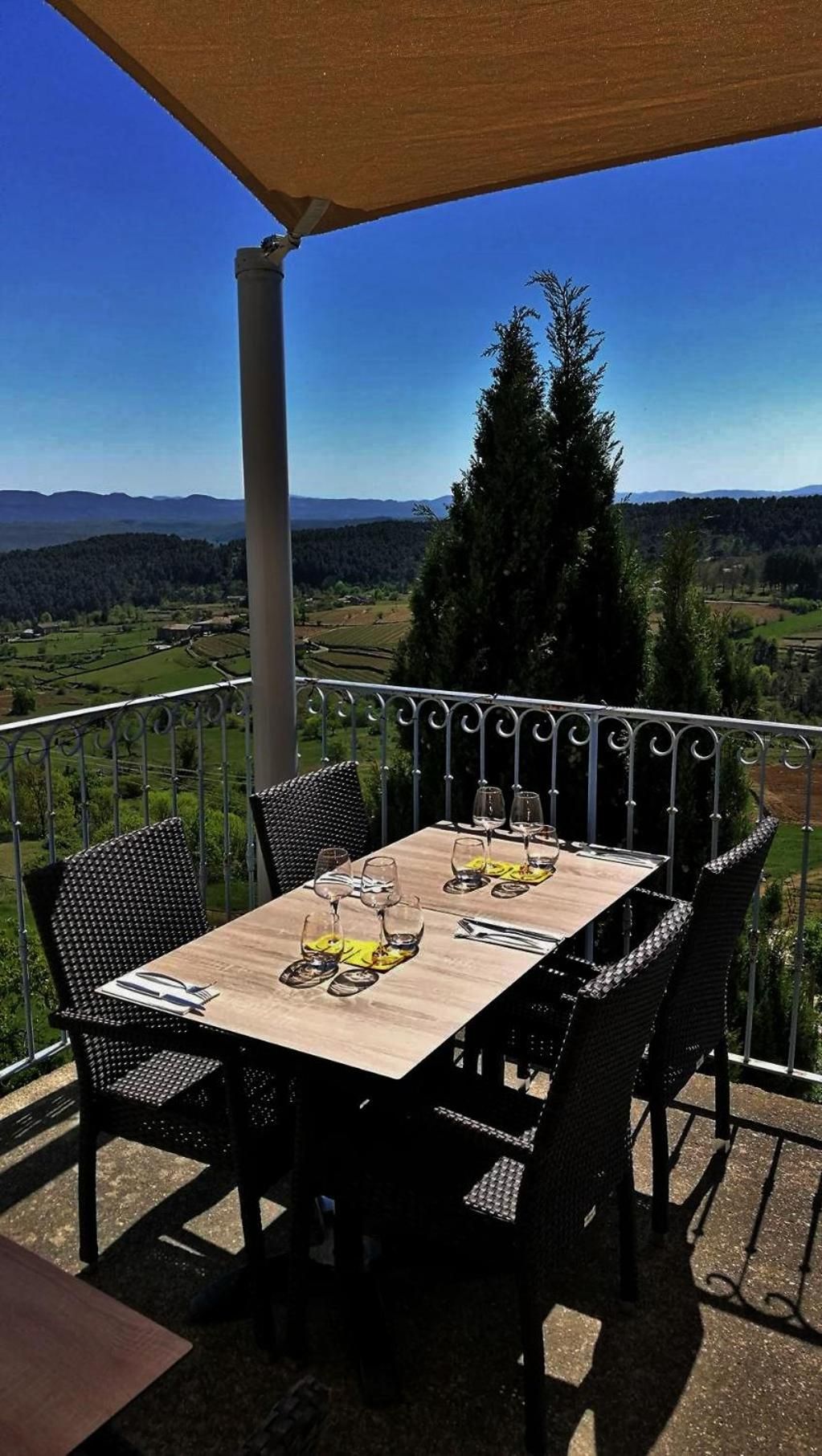 A terrace with a table set for dining, overlooking a scenic landscape.