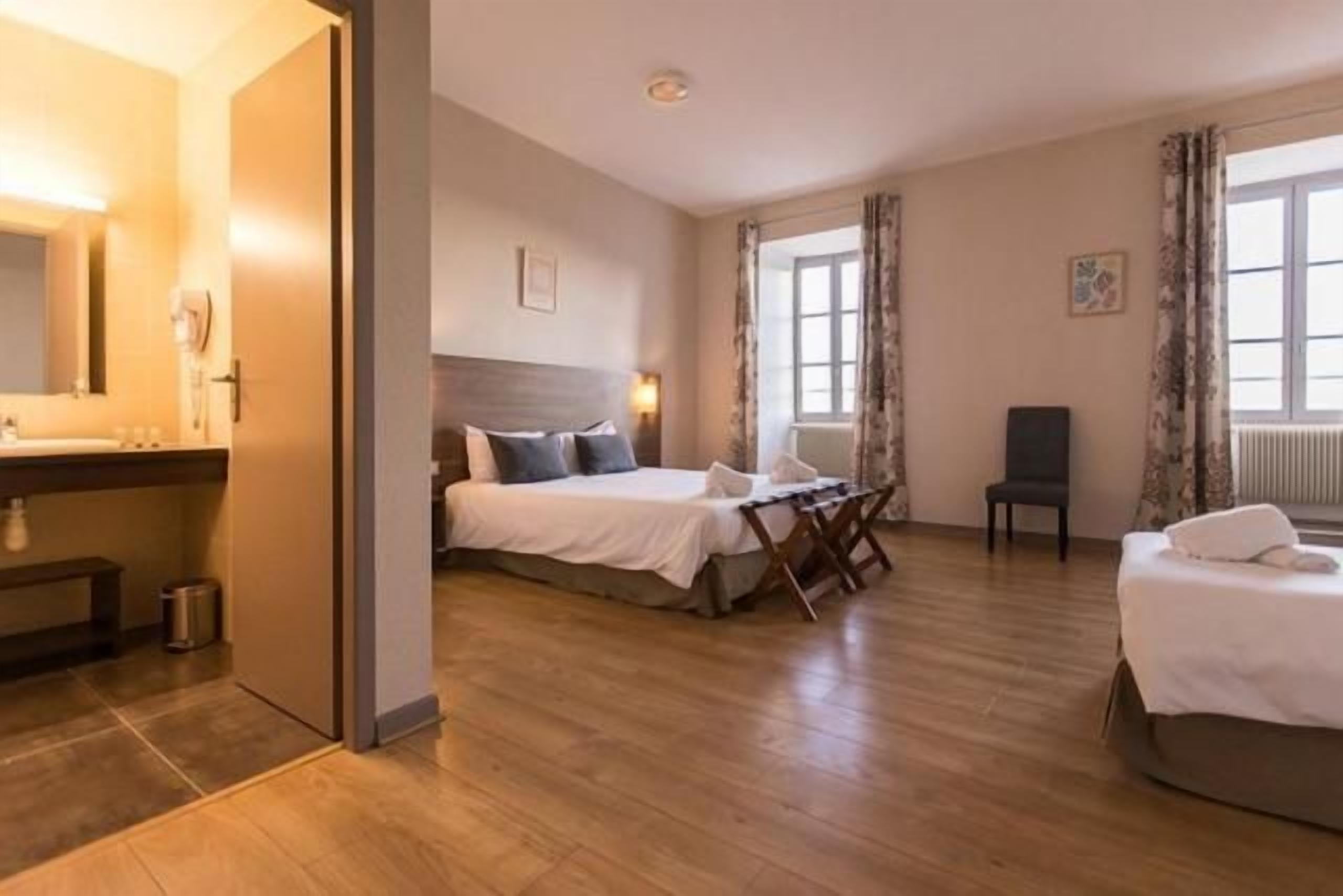 Una habitación de hotel con cama, escritorio, silla y zona de baño.